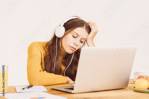 Young girl fell asleep in front of laptop. Cute woman is bored, tired or overworked. Cozy home environment