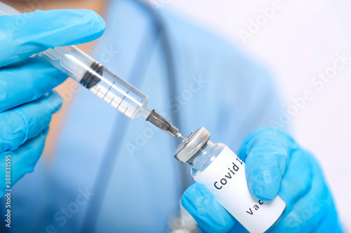 A gloved doctor fills a syringe with a vaccine to prevent the virus.