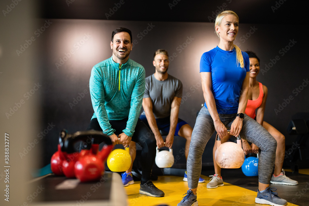 Fototapeta premium Young sporty people working out together with kettle bells in a gym.