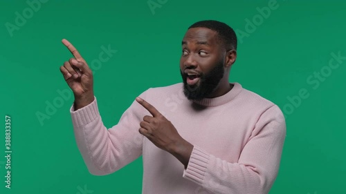 Close up portrait of a happy young man pointing finger showing copy space on Green Screen, Chroma Key