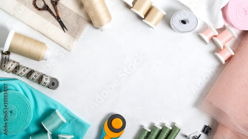 Composition with threads and sewing accessories on white background. Frame of tailoring tools and sewing supplies for text,sewing kit. Top view, horizontal orientation.