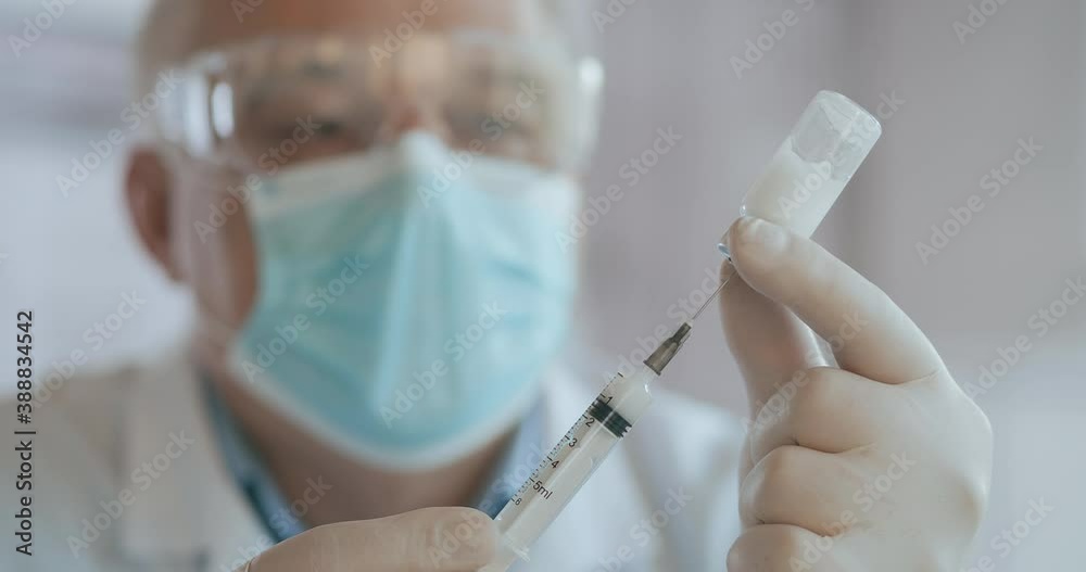 Close up shot of unrecognizable nurse or doctor in gloves filling syringe from ampule with covid-19 vaccine. Nurse filling injection syringe from vial.