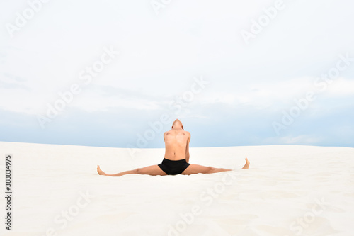 Young man in yoga pose samakonasana on the beach