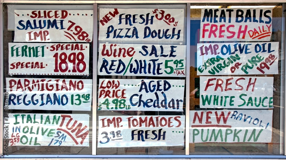 Italian deli window filled with hand lettered butcher paper food specials.