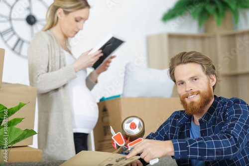 young couple carrying big cardboard box at new homemoving house