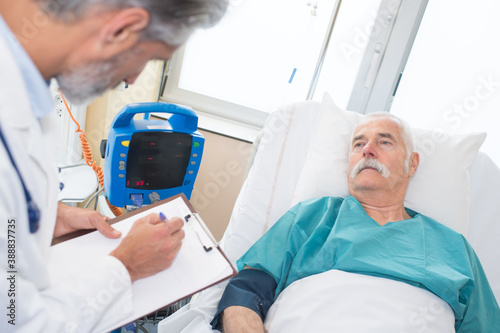 doctor noting hospital patients blood pressure reading