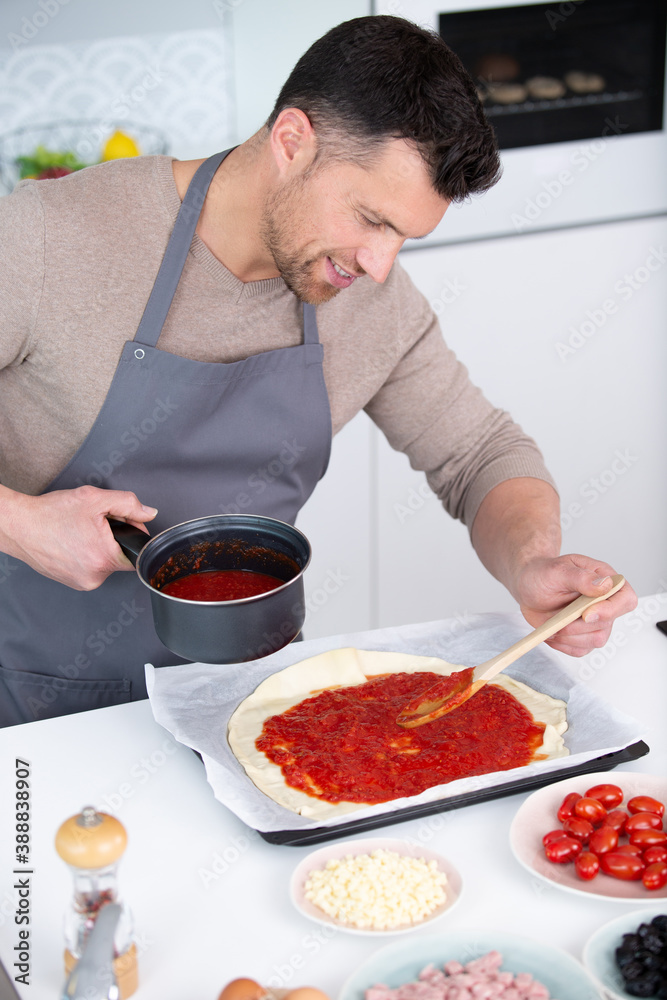 young male cook preparing delicious pizza