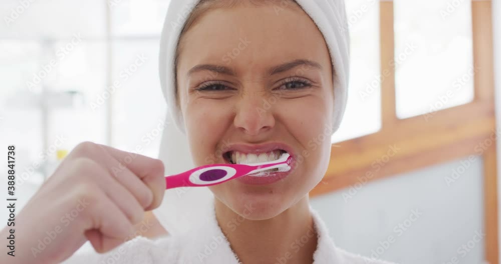 Portrait of woman in bathrobe brushing teeth Portrait of woman in bathrobe brushing teeth