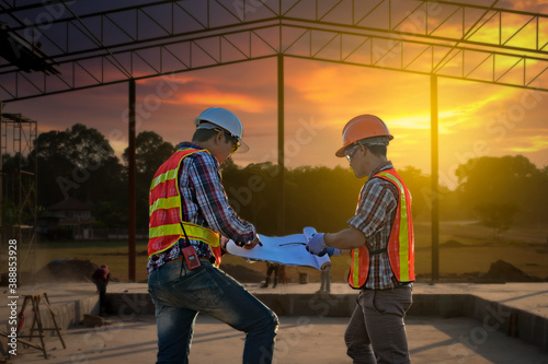 Teams of Business Engineers looking for blueprints in construction sites through blurry construction sites at sunset.