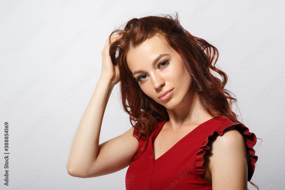 Studio glamor portrait of a beautiful woman with luxurious hair on a light background.