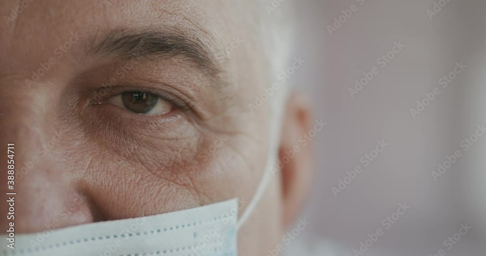 male doctor or nurse in uniform, mask looking straight at camera. Close up of eye. slow motion