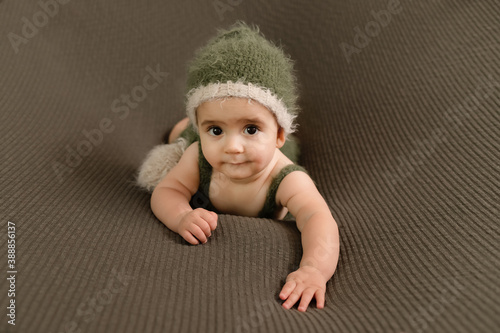 Cute newborn baby in the dark green hat. Happy baby on a green background. Closeup portrait of newborn baby. Baby goods packing template. Nursery. Medical and healthy concept. Christmas. New Year