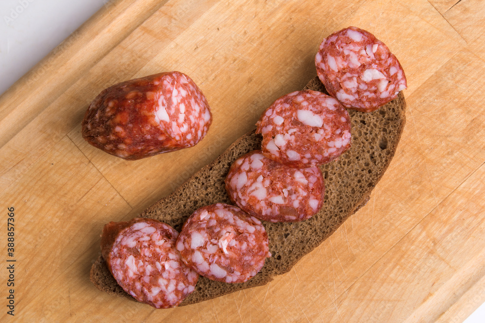 Slices of delicious smoked sausage on a wooden background, and bread Slices of delicious smoked sausage on a wooden background, and bread