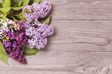 Various varieties of lilacs on the left side of a wooden table with copy space
