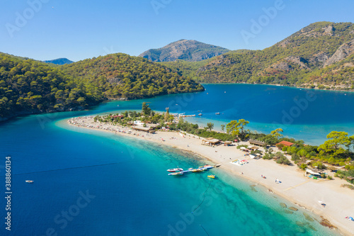 long sand beach in emerald lagoon and green mountains with blue sky and copy space