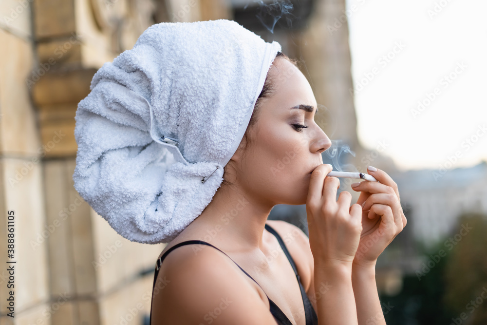 Sexy young woman in black underwear with towel on head smoking