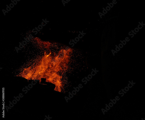 fire flames with sparks on a black background. In the foreground  the iron hammer silhouette is visible.