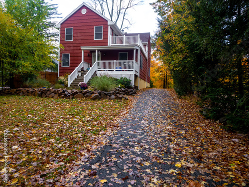 fallen leaves in the garden and driveway of red suburban house in autumn