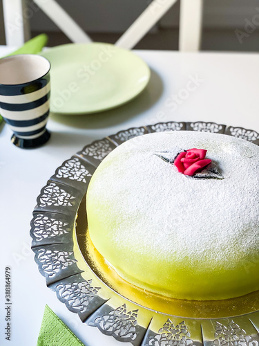 Green marzipan cake on silver cake plate and set table. Pink marzipan rose. Swedish birthday cake. Födelsedag. Prinsesstårta. photo