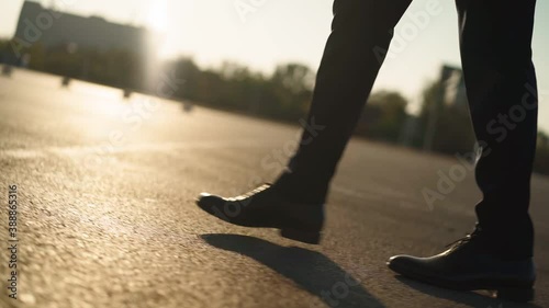 Close-up of the legs of a business man in black shoes and a suit walking confidently around the city to work in the office. Business and finance concept. Slow motion