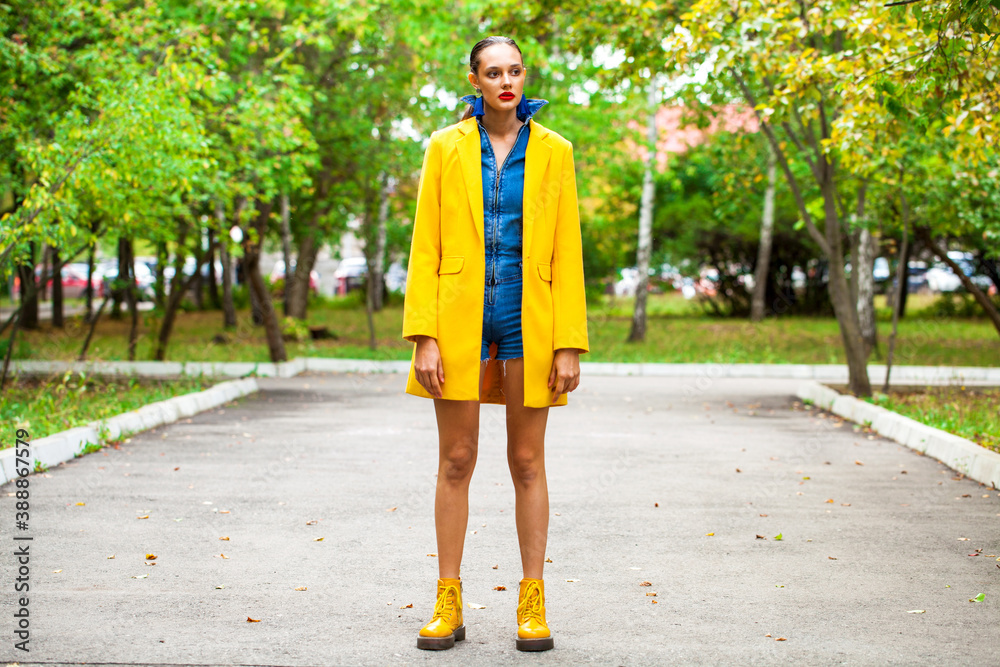 Fashion model in a yellow coat шт autumn park