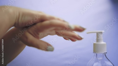 Woman treats hands with antiseptic gel, close up, hand hygiene