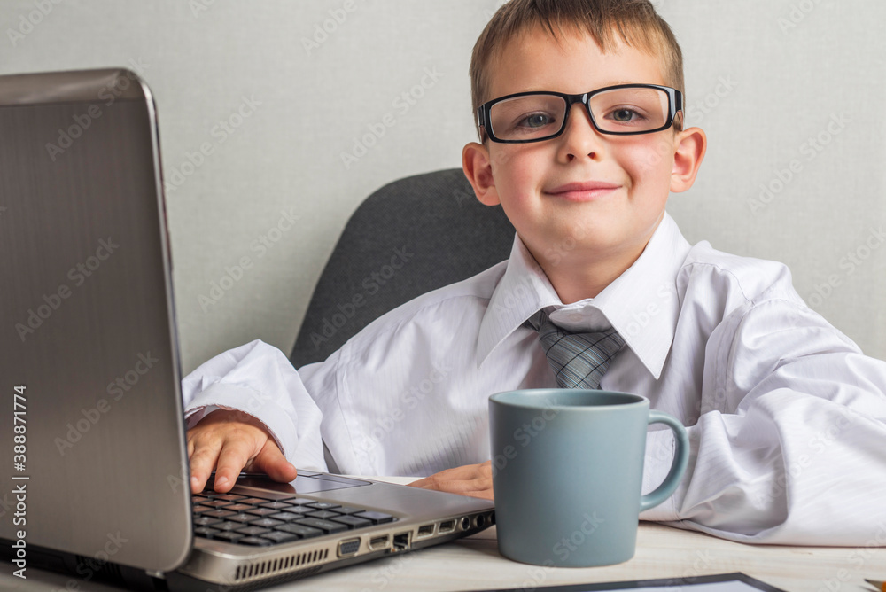 An adorable child is working on a laptop in suit and glasses. Little boss in the office. Children pretend to be adults An adorable child is working on a laptop in suit and glasses. Little boss in the office. Children pretend to be adults