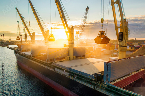 Obraz na plátně Large international transportation vessel in the port, loading grain during sunrise for export in the sea waters