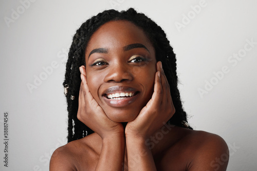Close-up of young black attractive woman with beautiful smile, posing over white background. Skin care concept.