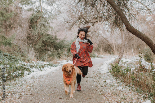 Woman and Dog Running on Snowy Path