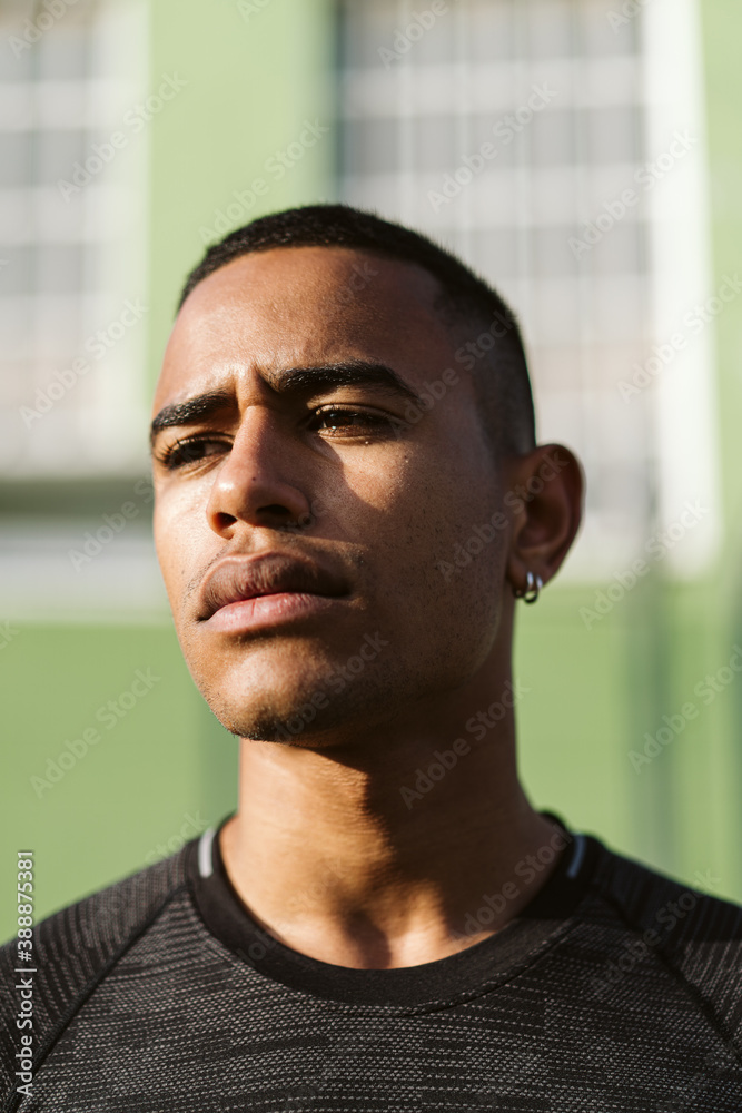 Serious black athlete near green building Serious black athlete near green building