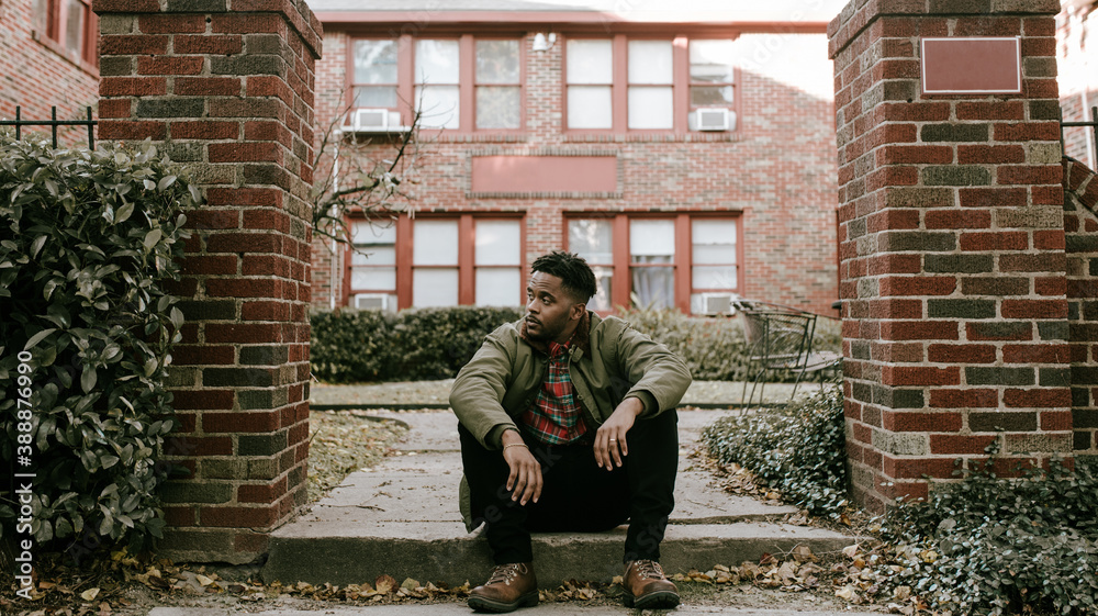 Man in green jacket and brown boots standing outside and sitting on stoop Man in green jacket and brown boots standing outside and sitting on stoop