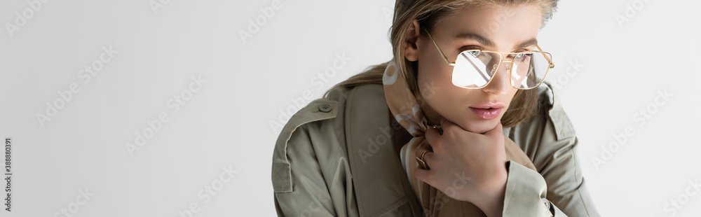 Φωτογραφία elegant woman in trench coat, glasses and scarf posing isolated on white, banner