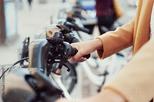 woman in urban station with electric bicycles to rent and move around the city close up