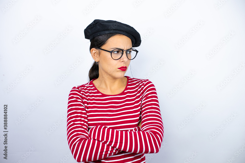 Young beautiful brunette woman wearing french beret and glasses over white background thinking looking tired and bored with crossed arms Young beautiful brunette woman wearing french beret and glasses over white background thinking looking tired and bored with crossed arms
