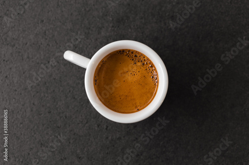 Cup of hot espresso coffee on black textured table.