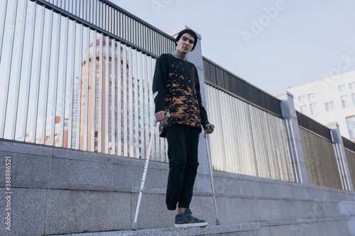 invalid guy stands on crutches on the street