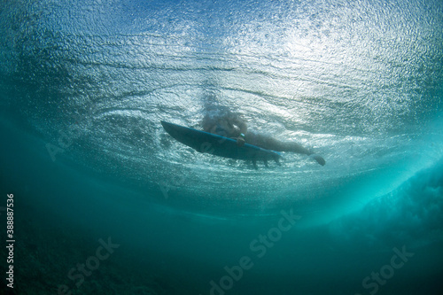 A feamle surfer is duck diving under a wave in Bali. Bubbles are surrounding her. photo
