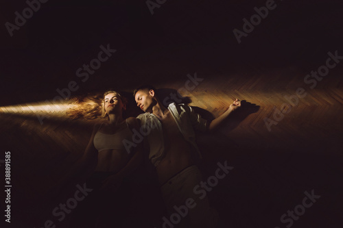 A young man and woman lie on the sun ray oin the dark room photo