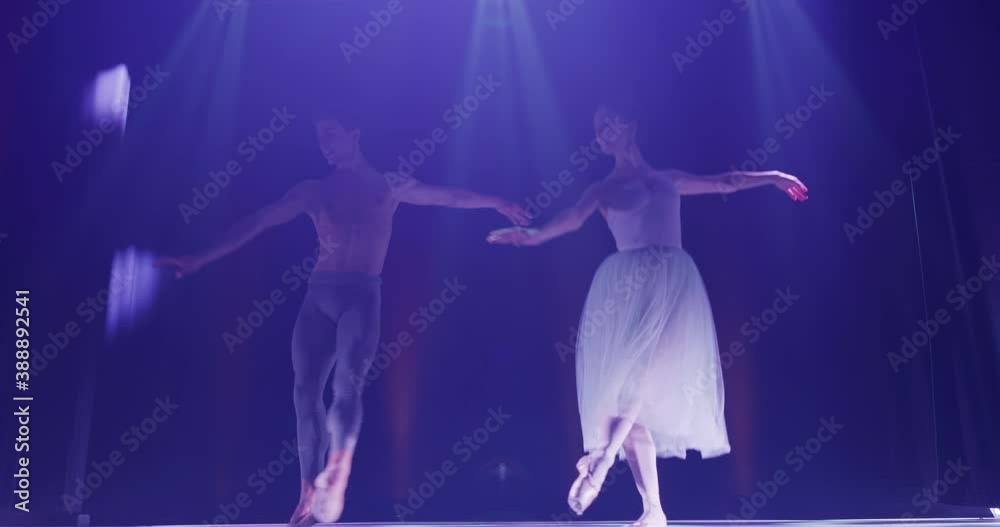 Cinematic shot of young couple of classical ballet dancers is performing a choreography on classic theatre stage with spotlights before start of a show. Cinematic shot of young couple of classical ballet dancers is performing a choreography on classic theatre stage with spotlights before start of a show.