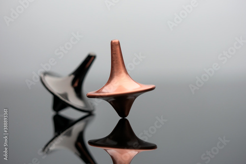 Playing with two beautiful spinning tops spinning on glass table