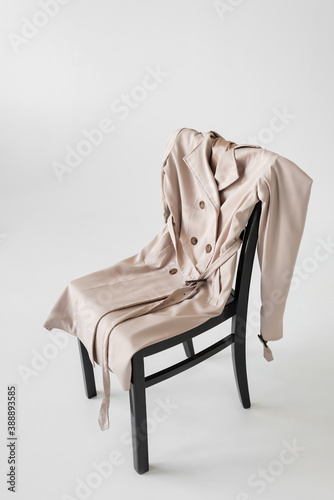 trendy trench coat on chair and white background