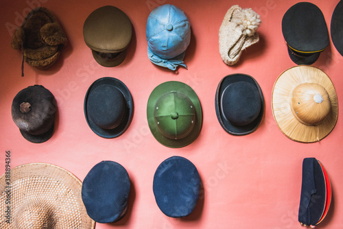 The collection of various hats on the pink wall.