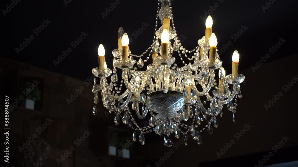 Retro chandelier hanging in dark room, beautiful lamp of vintage style illuminating all around. Crystal details decorating chandelier, antique object decorating room and creating special retro
