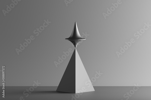 Three dimensional render of metallic top spinning on top of geometric pyramid photo