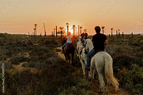 Family riding horses on landscape against sky during sunset