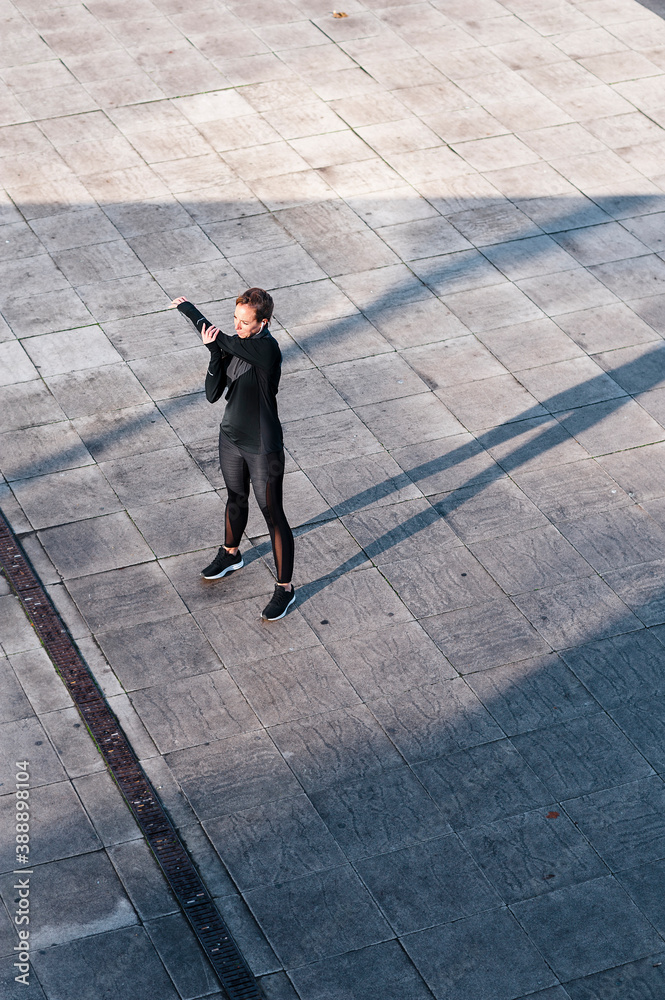 Female athlete stretching hands while standing on rooftop Female athlete stretching hands while standing on rooftop