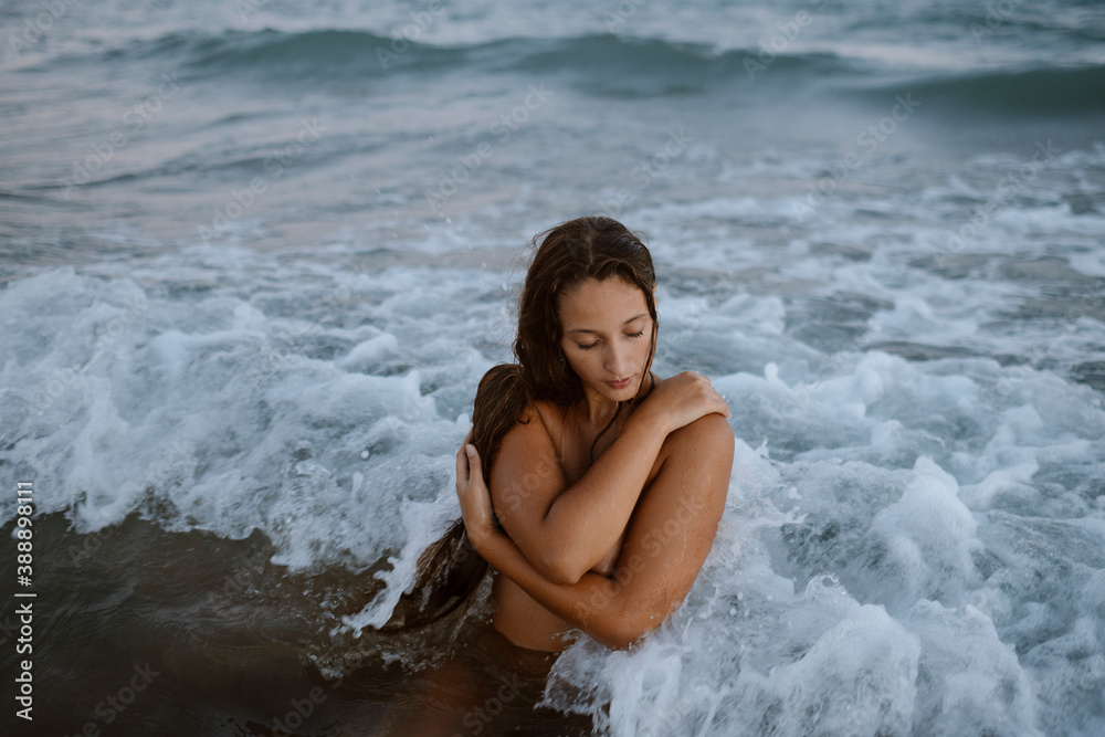 Woman with arms crossed taking bath in water at beach Woman with arms crossed taking bath in water at beach