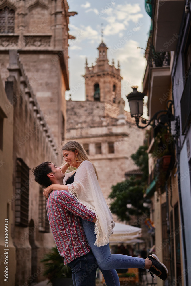Happy man picking up woman while standing in city Happy man picking up woman while standing in city