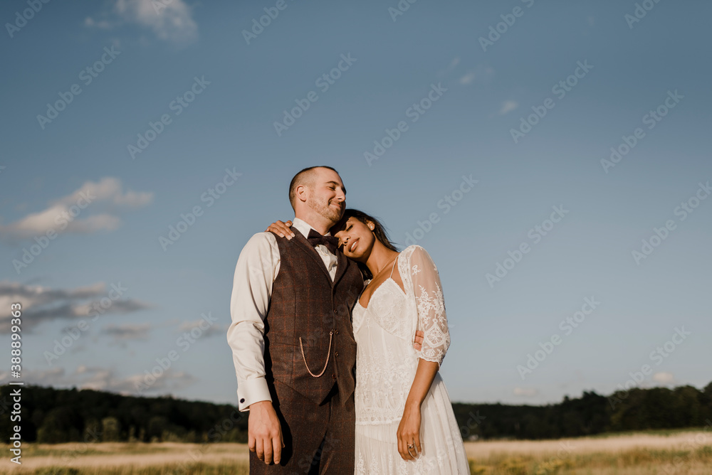 Bride leaning on bridegroom's shoulder while standing at field Bride leaning on bridegroom's shoulder while standing at field